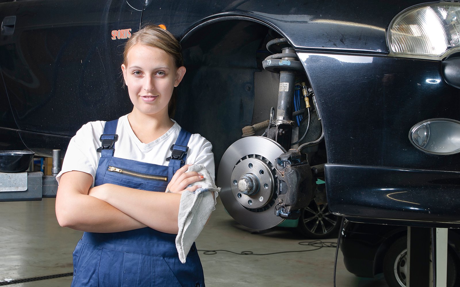 Kfz-Mechanikerin vor einem Auto