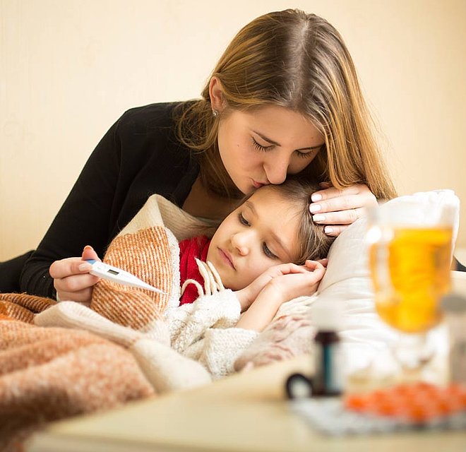 Eine Mutter umarmt und tröstet ihre kranke Tochter.