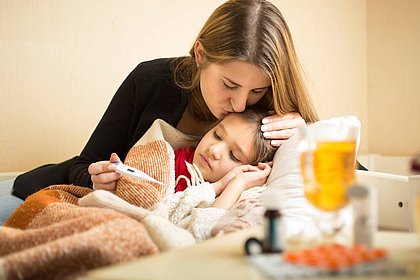 Eine Mutter umarmt und tröstet ihre kranke Tochter.